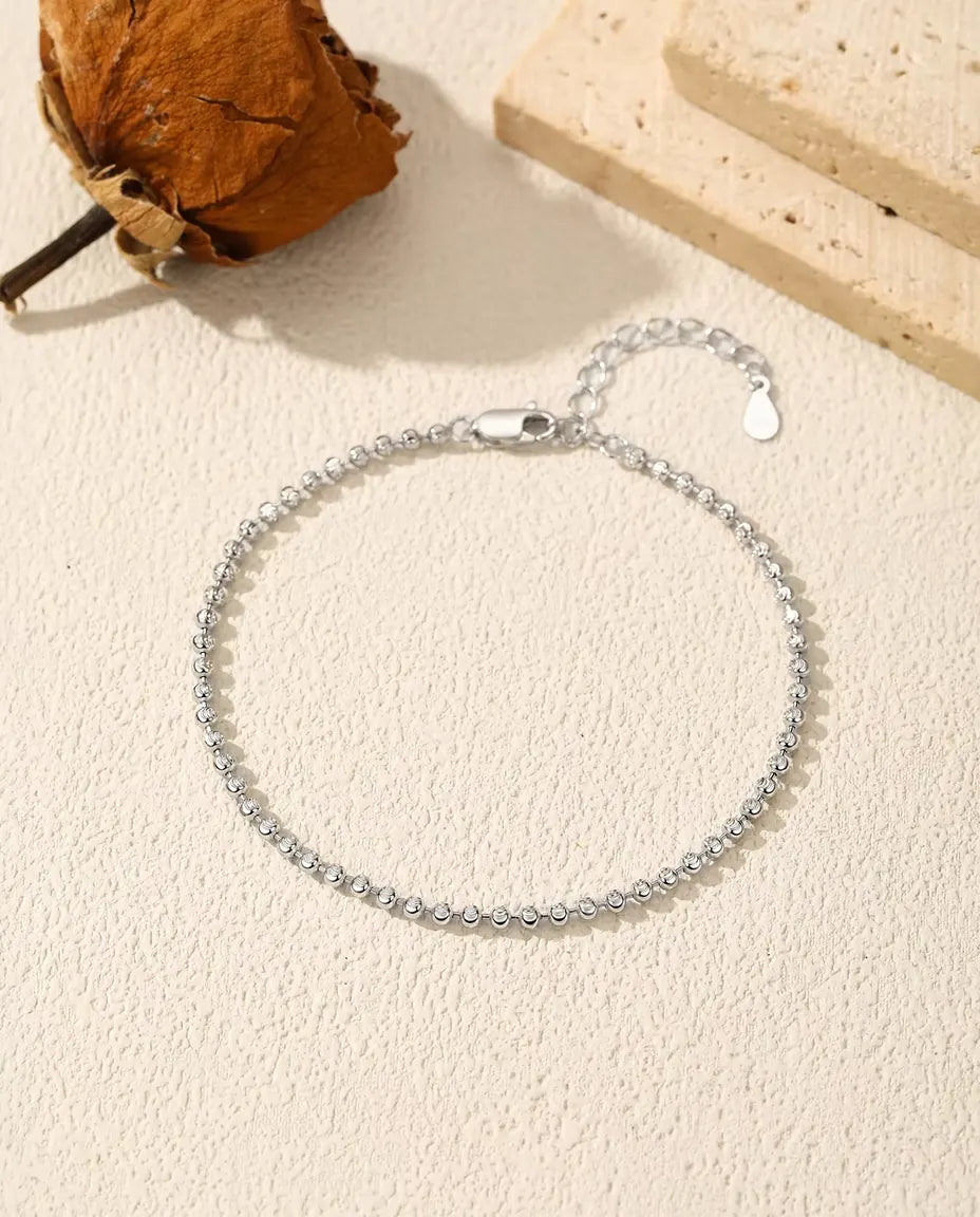 Armband med Facetterade Silverkulor i 925 Sterlingsilver - liggande på en ljus strukturerad yta med lås och förlängningskedja