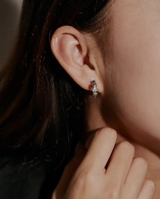 Moissanite Örhängen med Kors i 925 Sterlingsilver - burna i en modells öra, handen nära ansiktet