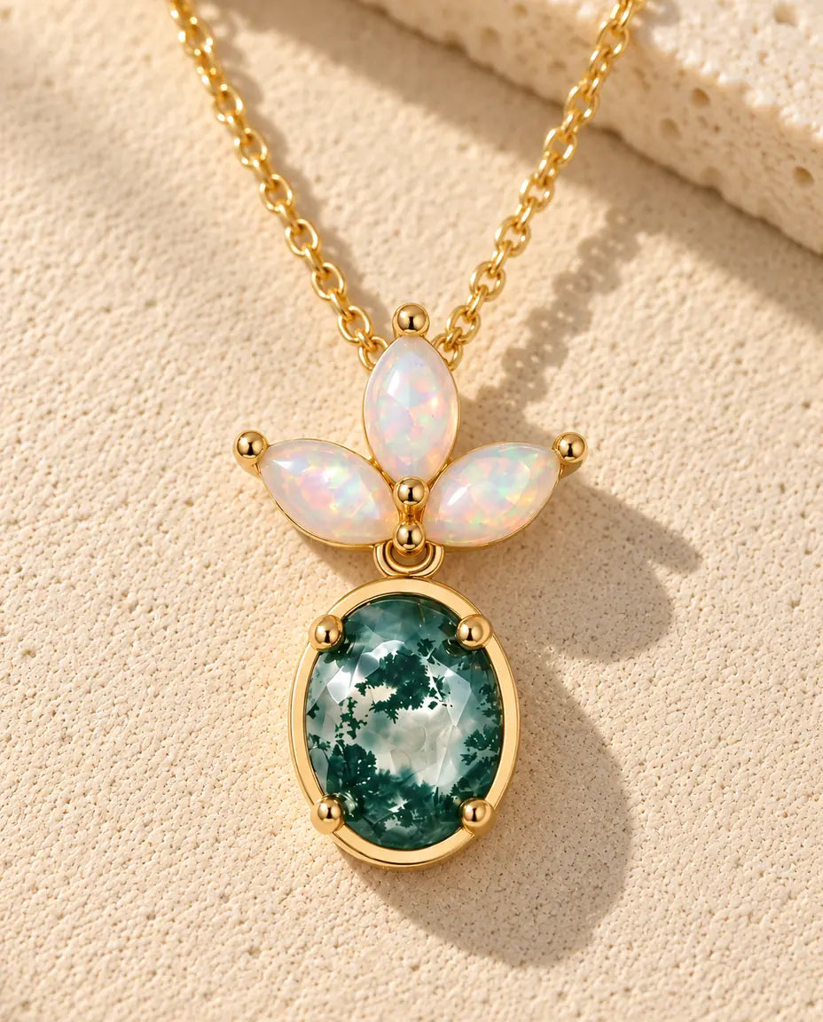 Moss Agate och Opal Halsband i Guldpläterat 925 Sterlingsilver - liggande på en ljus strukturerad yta bredvid ett travertinblock