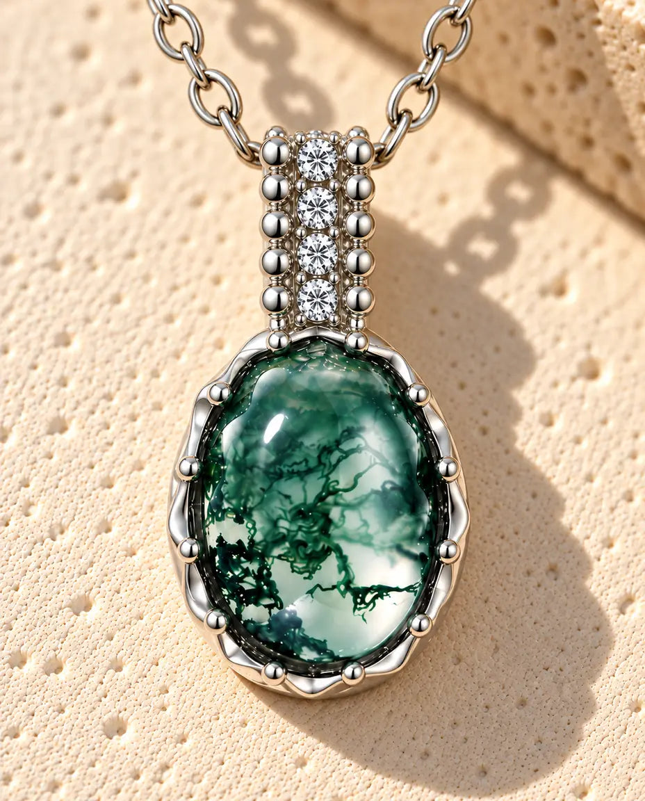 Oval Moss Agate Halsband i 925 Sterlingsilver - liggande på en ljus strukturerad yta bredvid ett travertinblock