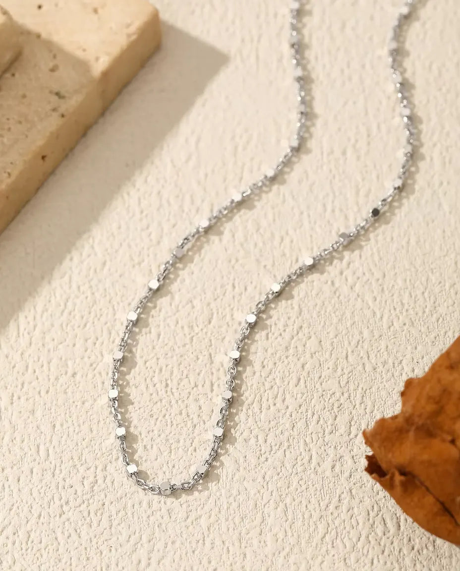 Halsband med Paljettkedja i 925 Sterlingsilver - draperat på en ljus yta bredvid en travertinplatta