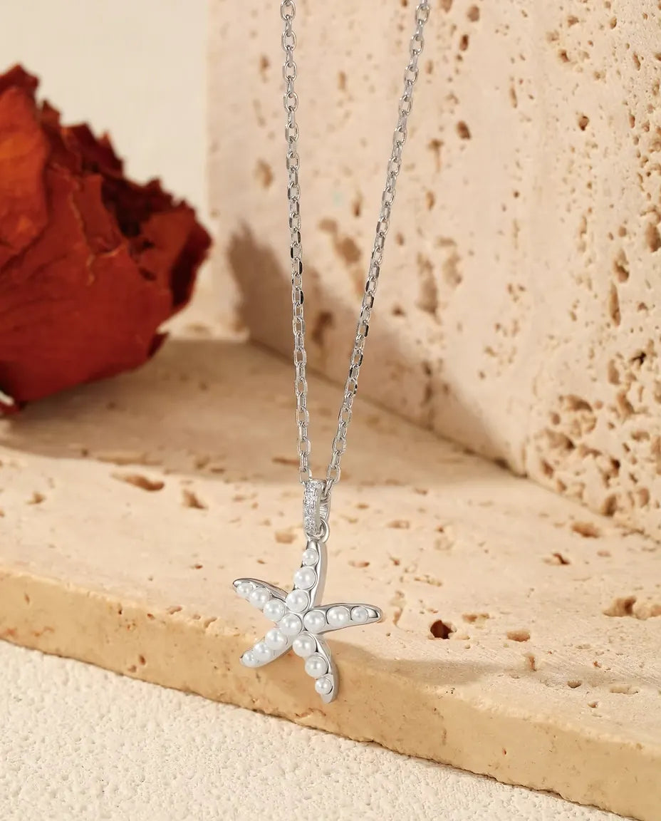 Halsband med Sjöstjärna i 925 Sterlingsilver - hänget över kanten av en travertinplatta
