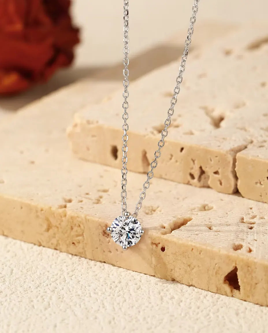 Moissanite Halsband 1 ct i 925 Sterlingsilver - hänget över kanten av en travertinplatta