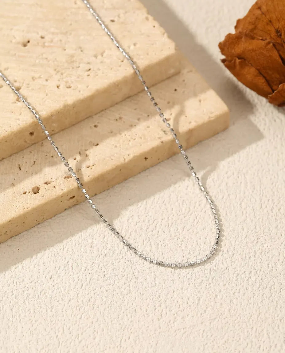 Halsband med Diamantslipad Kedja i 925 Sterlingsilver - draperat på en ljus yta bredvid en travertinplatta