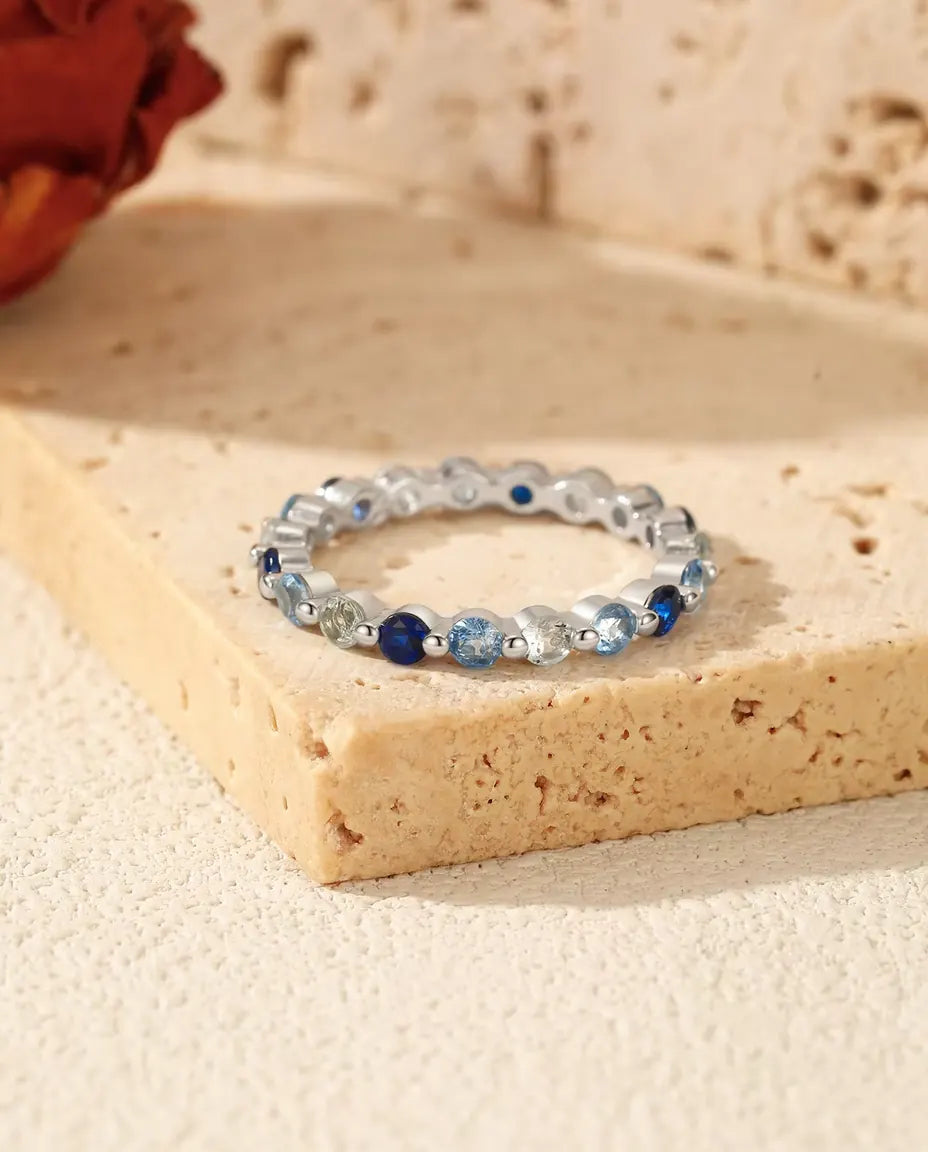 Ring med Blå Zirkonia Hela Varvet Runt i 925 Sterlingsilver - liggande på ett travertinblock
