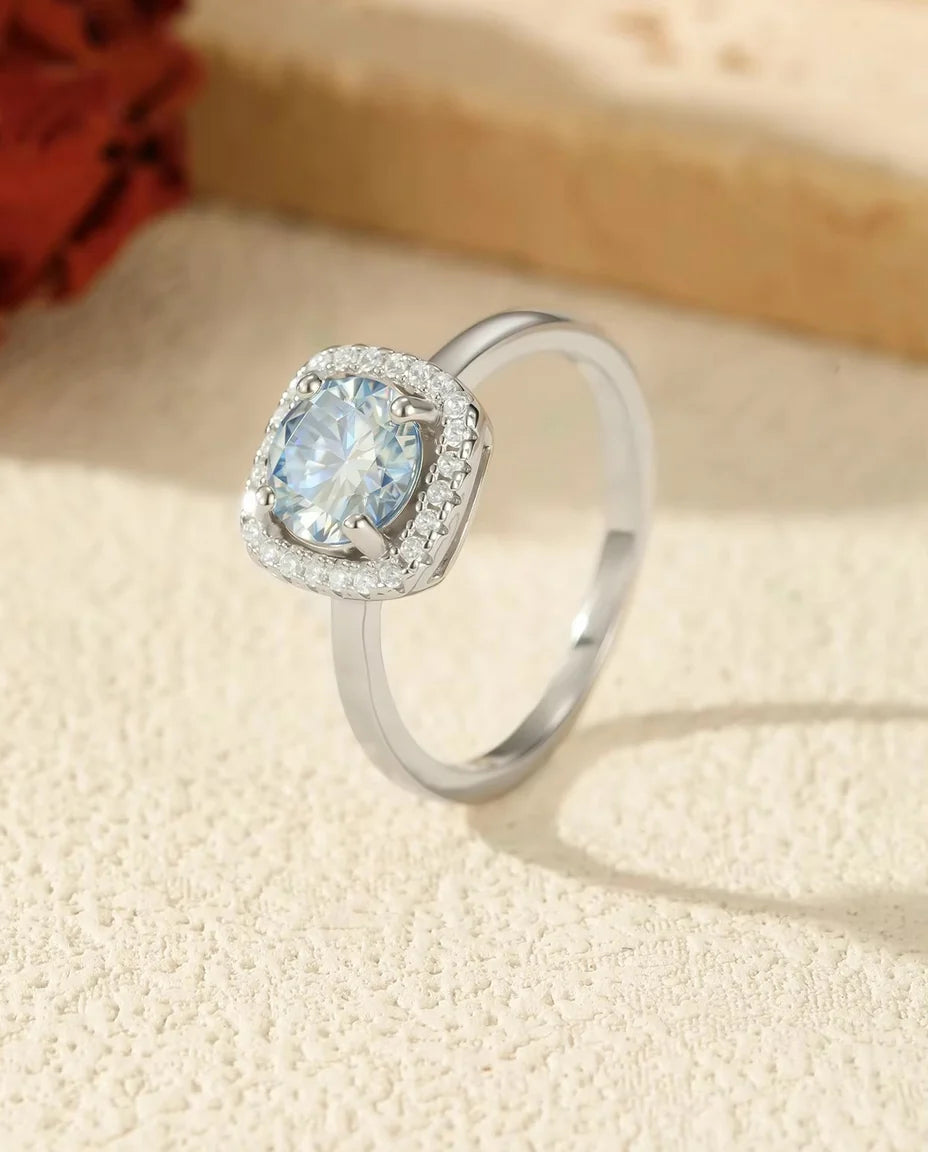 Moissanite Ring Havsblå 1 ct Halo - visad på ett travertinblock