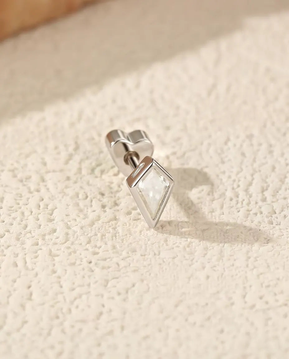 Stiftörhängen med Drakslipad Moissanit i 925 Sterlingsilver - liggande på sidan på en ljus strukturerad yta, hjärtformat lås på stiftet