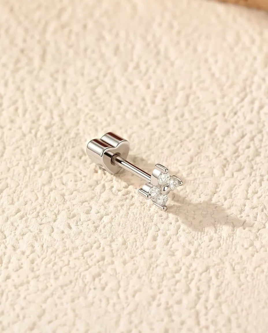 Stiftörhängen med Fyra Moissaniter i Fyrklöverform i 925 Sterlingsilver - liggande på sidan på en ljus strukturerad yta, hjärtformat lås på stiftet