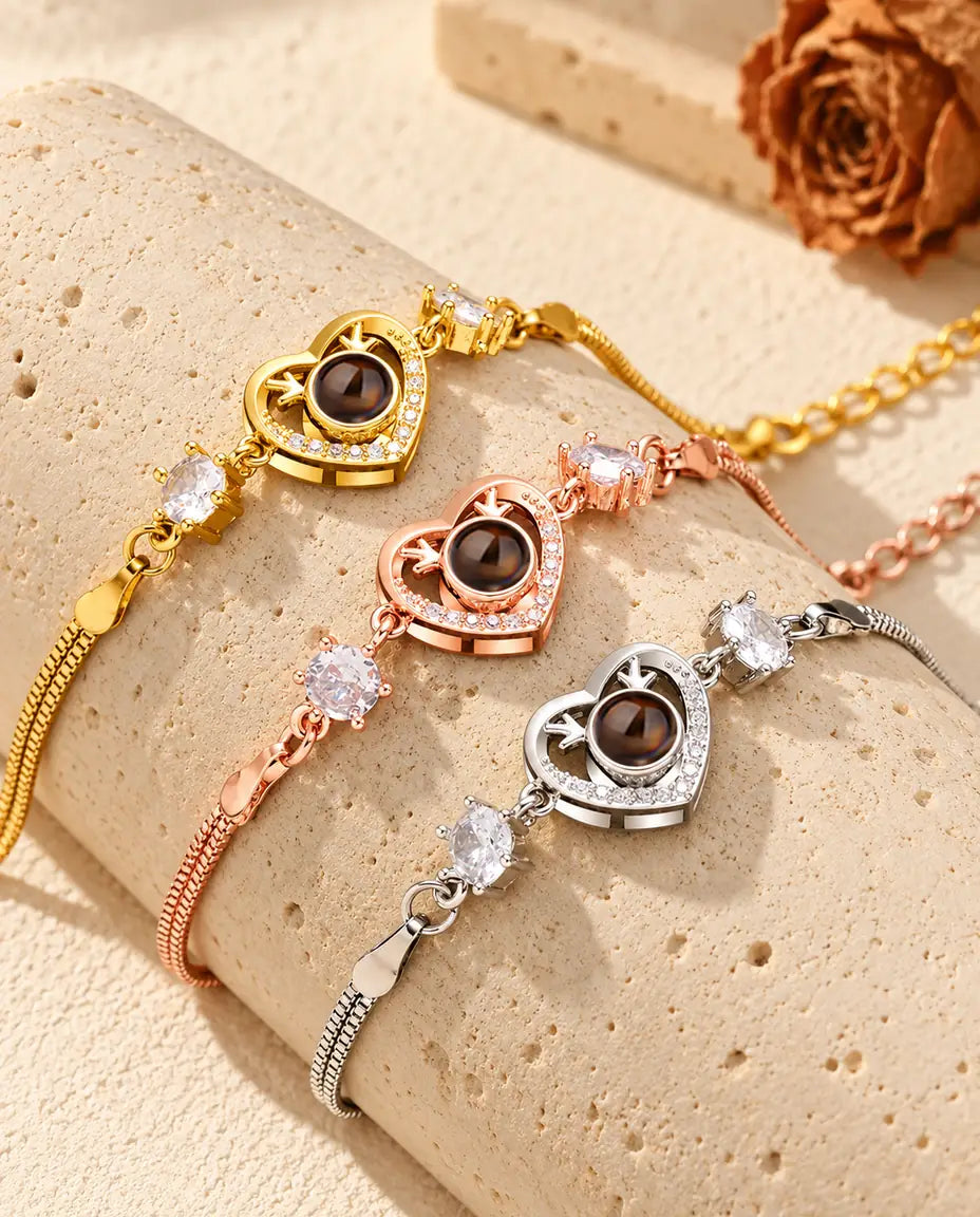 Tre armband med hjorthornshjärta i guldfärgat, roséguldfärgat och silverfärgat draperade över ett travertinblock