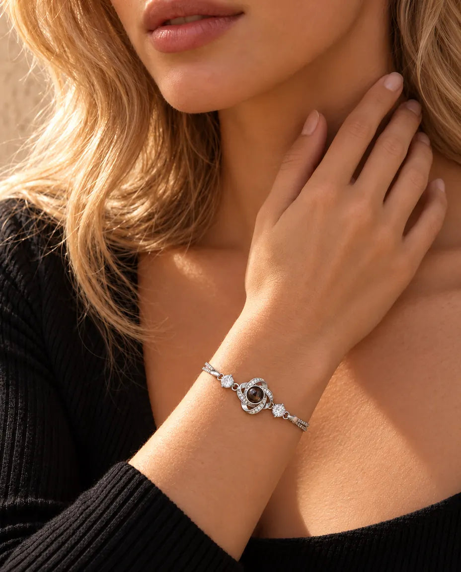 Kvinna som rör vid sidan av halsen och bär det silverfärgade armbandet med kärleksknut och bild inuti