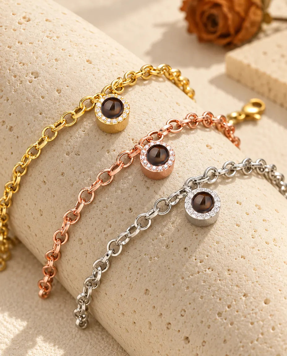 Guldfärgade, roséguldfärgade och silverfärgade armband med rund zirkoniaberlock draperade över travertin