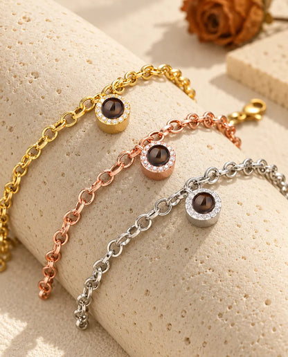 Guldfärgade, roséguldfärgade och silverfärgade armband med rund zirkoniaberlock draperade över travertin