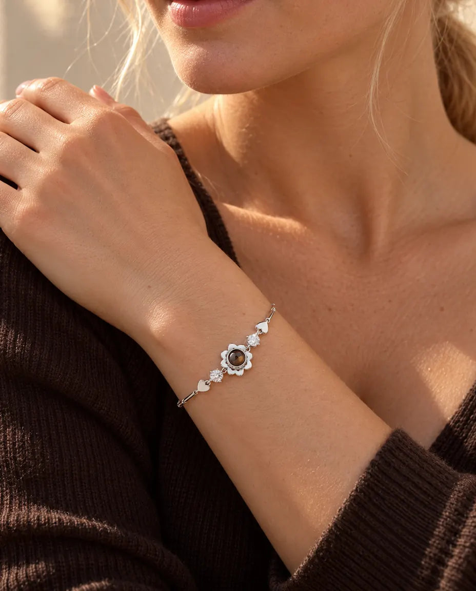 Kvinna som vilar handen mot axeln och bär det silverfärgade armbandet med klöverblomma och bild inuti