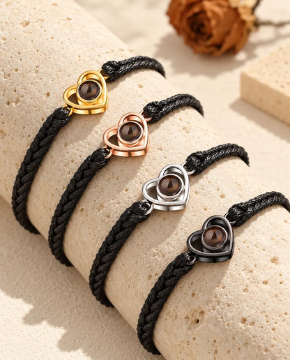 Fyra svarta flätade armband med öppet hjärta i varje färg på ett travertinblock