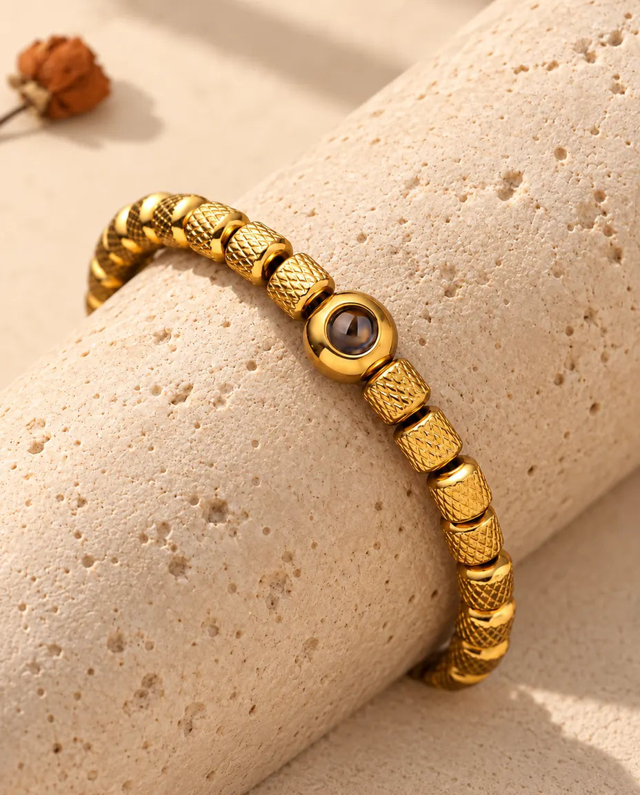 Närbild på den guldfärgade runda projektionspärlan mellan räfflade cylinderpärlor
