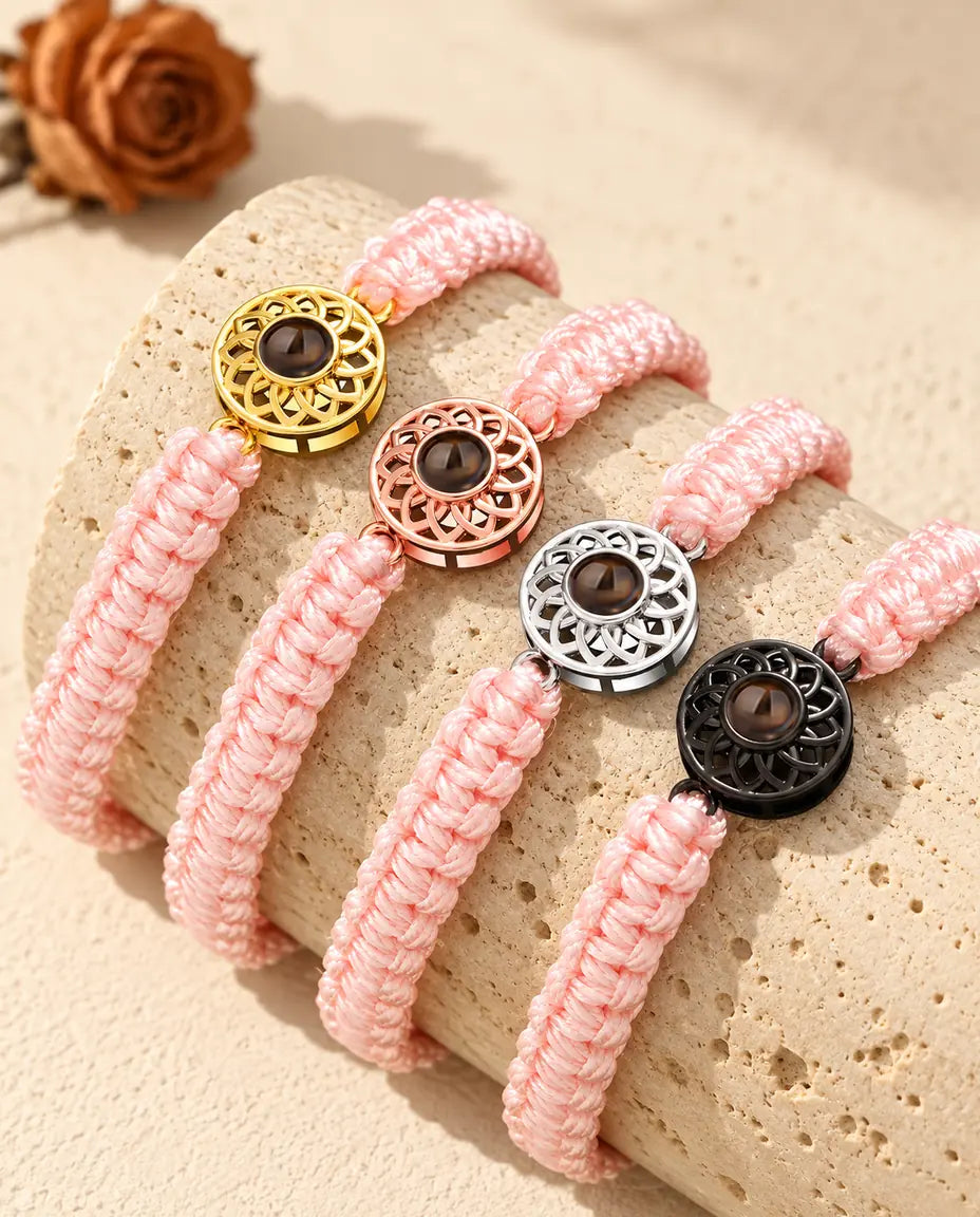 Armband med bild inuti på rosa flätad snodd med guldfärgade, roséguldfärgade, silverfärgade och svarta runda berlocker