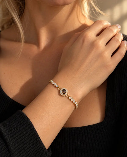 Närbild på det guldfärgade tennisarmbandet med haloberlock på en handled vid nyckelbenet