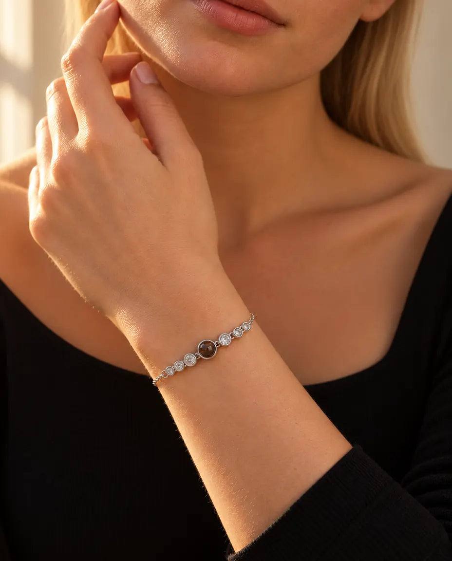 Kvinna som rör vid käklinjen och bär det silverfärgade armbandet med en rad stenar och bild inuti