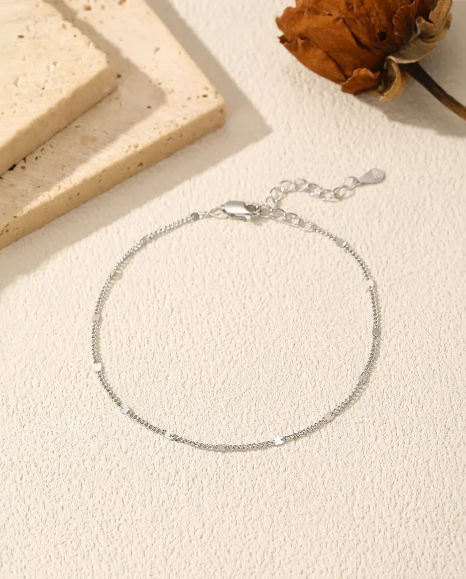Armband med Paljettkedja i 925 Sterlingsilver - liggande på en ljus strukturerad yta med lås och förlängningskedja