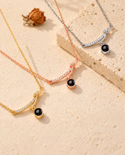 Halsband med böjd stav i silverfärgat, guldfärgat och roséguldfärgat draperade över travertin