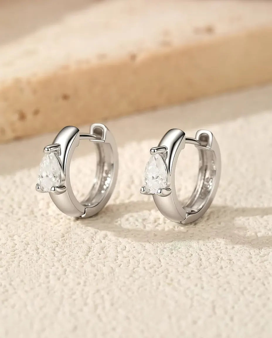 Örhängen med Droppslipad Moissanit i 925 Sterlingsilver - paret stående sida vid sida på en ljus strukturerad yta