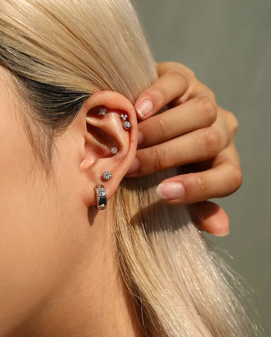 Breda Små Creoler med Oval Moissanite i 925 Sterlingsilver - buret av en modell som stryker håret bakom örat