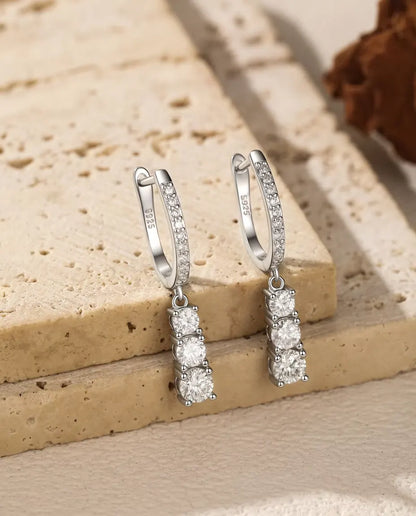 Moissanite Örhängen i 925 Sterlingsilver - paret hängande från kanten av en travertinplatta