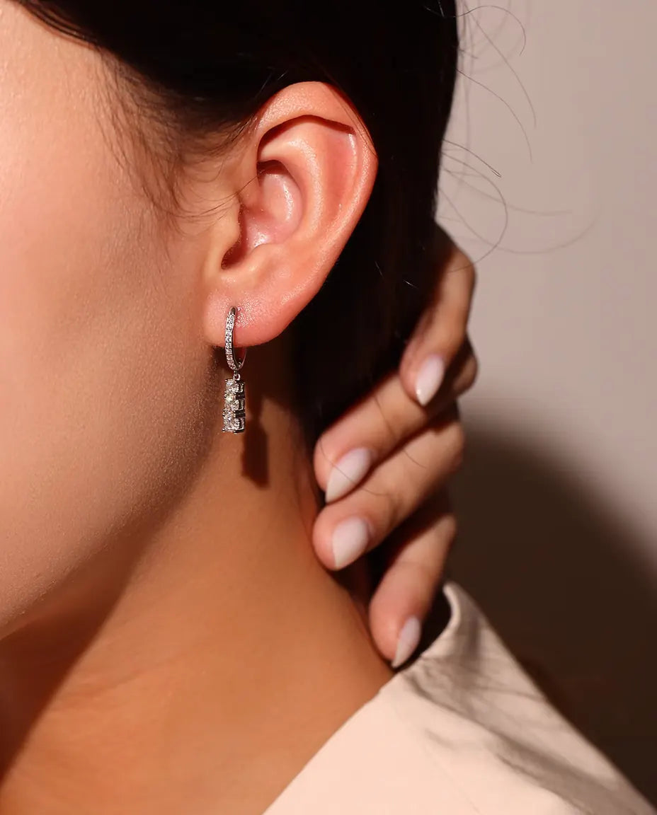 Moissanite Örhängen i 925 Sterlingsilver - burna i en modells öra, fingrarna vid halsen