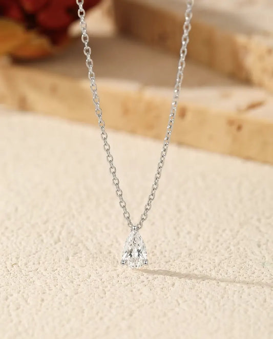 Moissanite Halsband 1 ct i 925 Sterlingsilver - hänget på en ljus yta bredvid en travertinplatta