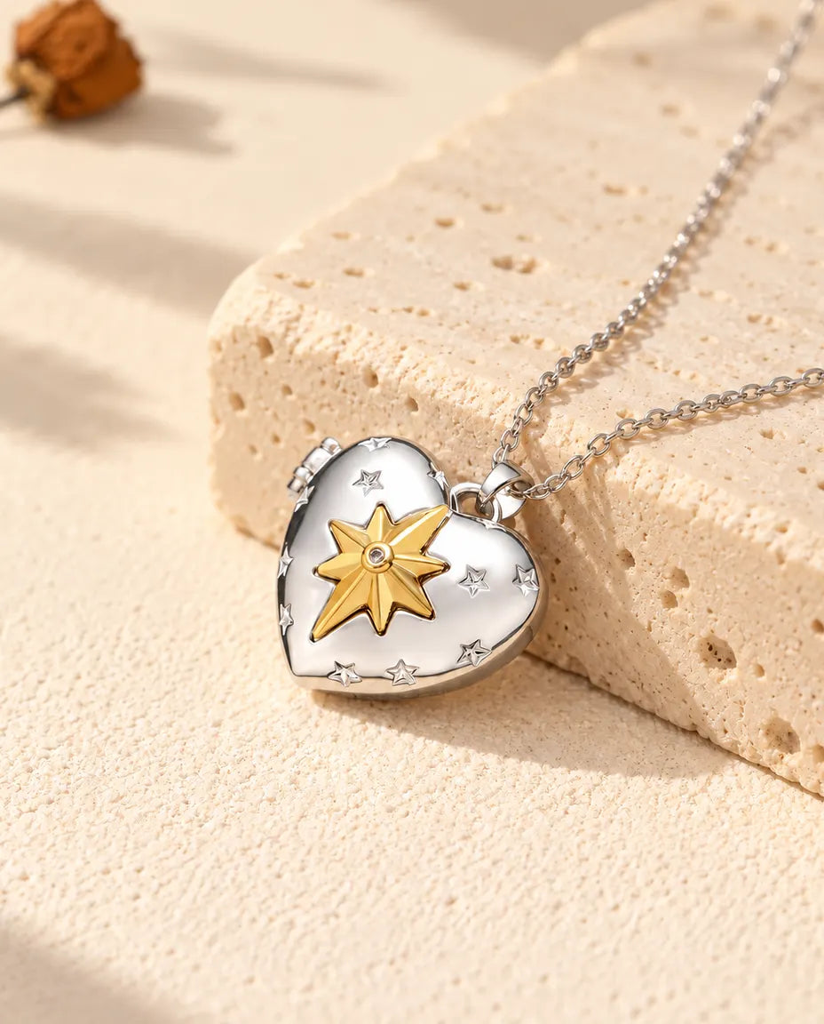 Personlig silverfärgad hjärtmedaljong med en guldfärgad nordstjärna på locket, lutad mot ett travertinblock