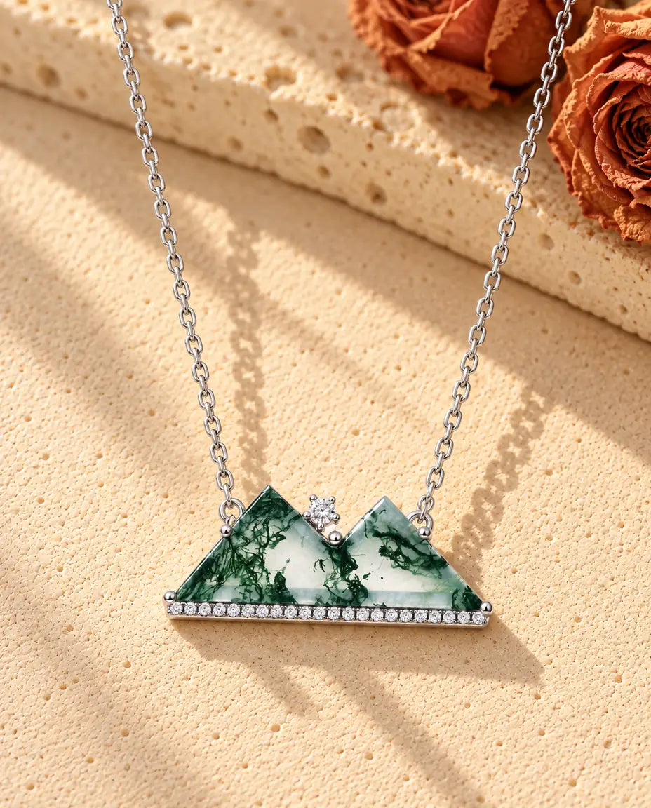 Moss Agate Halsband med Berg i 925 Sterlingsilver - liggande på en ljus strukturerad yta bredvid ett travertinblock