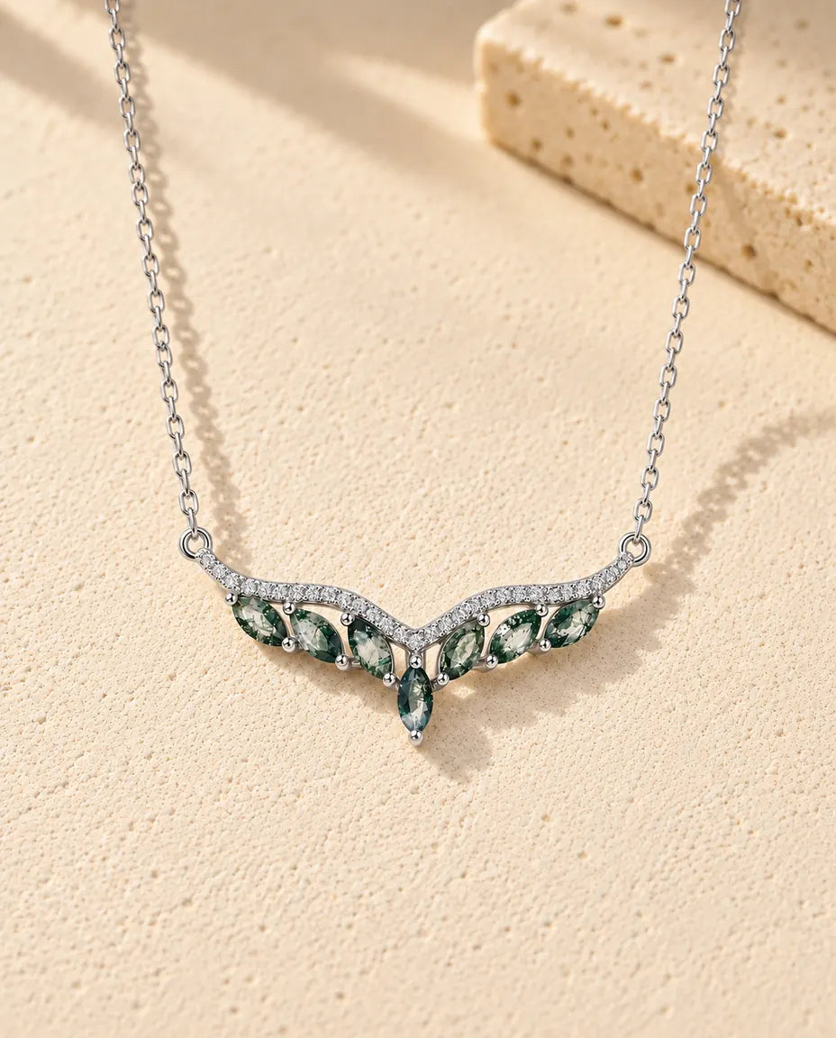 Moss Agate Halsband i 925 Sterlingsilver - liggande på en ljus strukturerad yta bredvid ett travertinblock