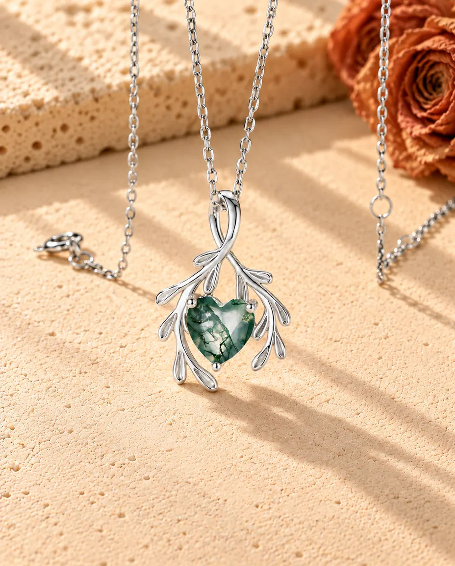 Moss Agate Halsband med Hjärta och Grenar i 925 Sterlingsilver - fotograferat snett på en ljus strukturerad yta