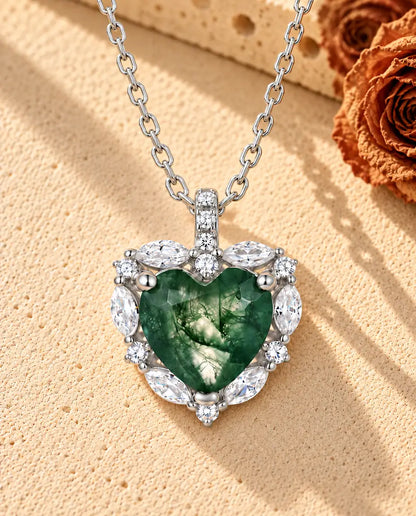 Moss Agate Halsband med Hjärta i 925 Sterlingsilver - liggande på en ljus strukturerad yta bredvid ett travertinblock