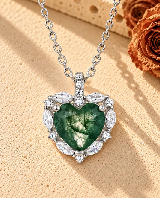 Moss Agate Halsband med Hjärta i 925 Sterlingsilver - liggande på en ljus strukturerad yta bredvid ett travertinblock