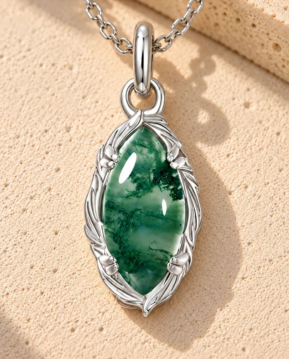 Marquise Moss Agate Halsband i 925 Sterlingsilver - liggande på en ljus strukturerad yta bredvid ett travertinblock