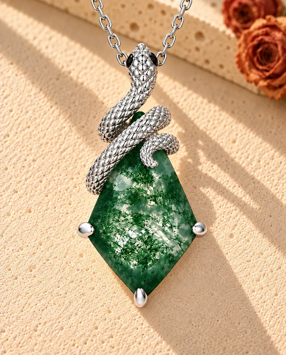 Moss Agate Halsband med Orm i 925 Sterlingsilver - liggande på en ljus strukturerad yta bredvid ett travertinblock