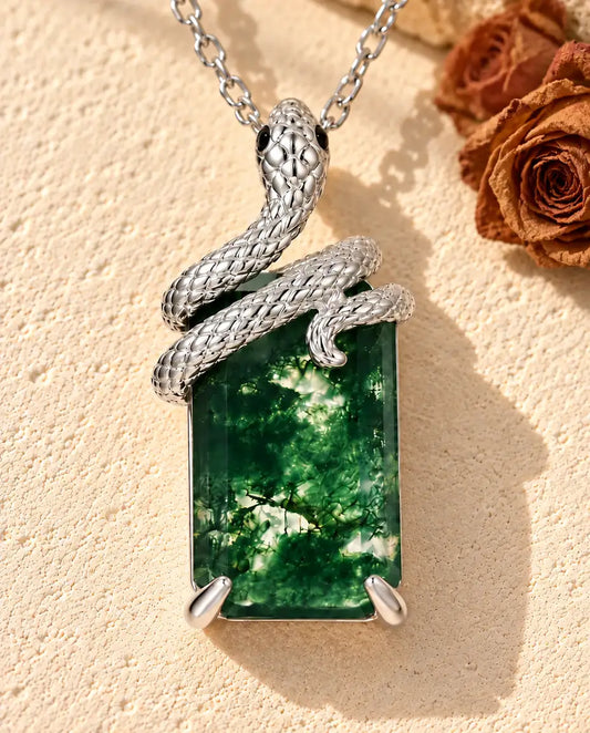 Moss Agate Halsband med Orm i 925 Sterlingsilver - liggande på en ljus strukturerad yta bredvid ett travertinblock