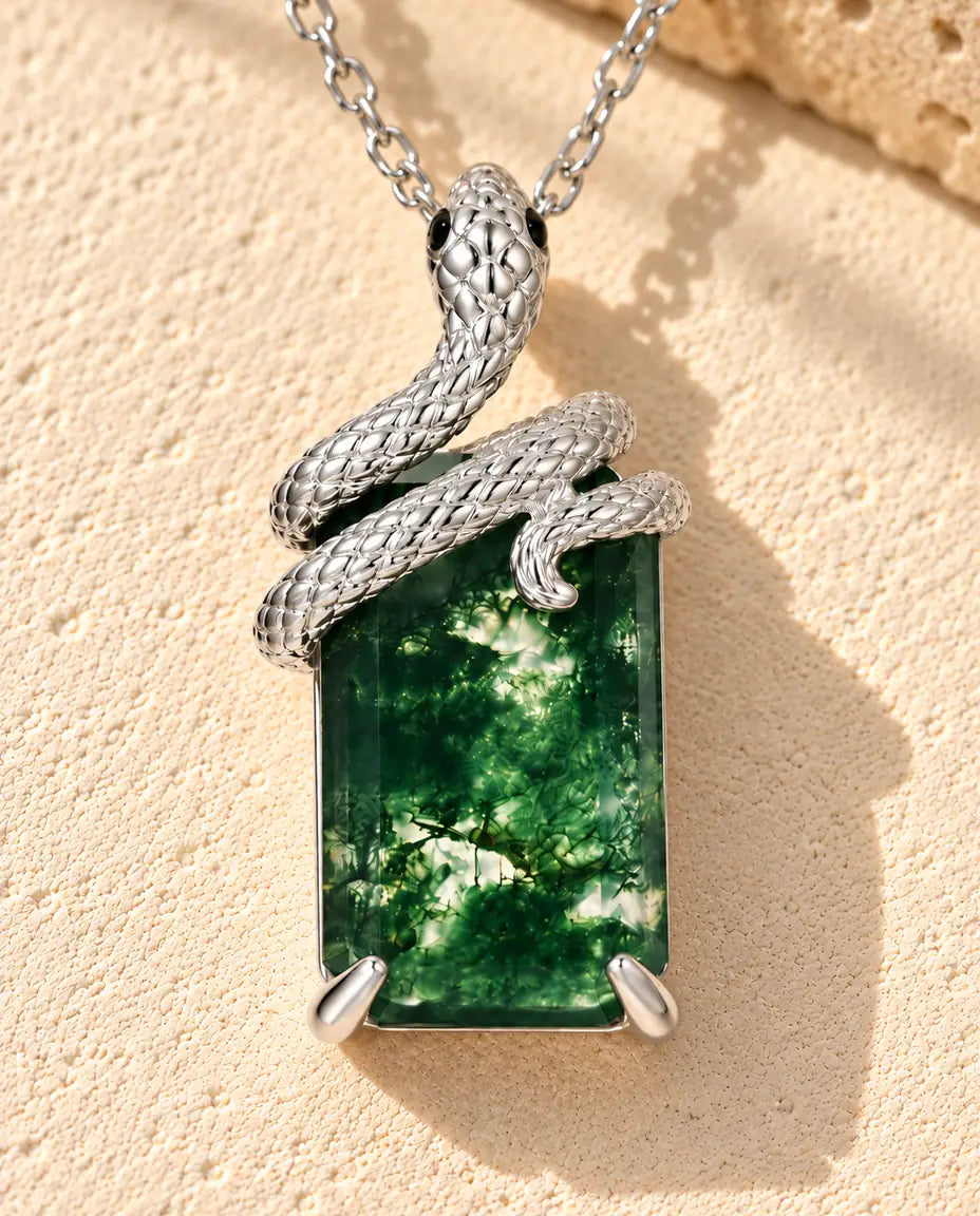 Moss Agate Halsband med Orm i 925 Sterlingsilver - liggande på en ljus strukturerad yta bredvid ett travertinblock