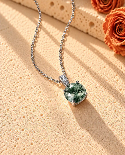 Moss Agate Halsband med Rund Solitär i 925 Sterlingsilver - fotograferat snett på en ljus strukturerad yta