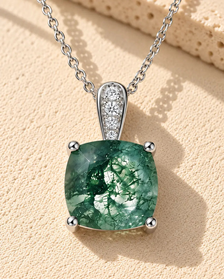 Moss Agate Halsband med Solitär i 925 Sterlingsilver - liggande på en ljus strukturerad yta bredvid ett travertinblock