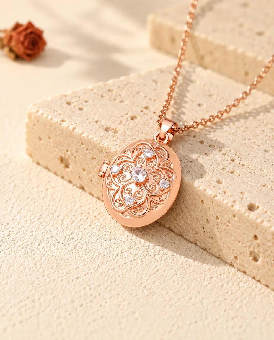 Roséguldfärgad oval fotomedaljong med en blomma av zirkonia på locket, vilande mot travertin