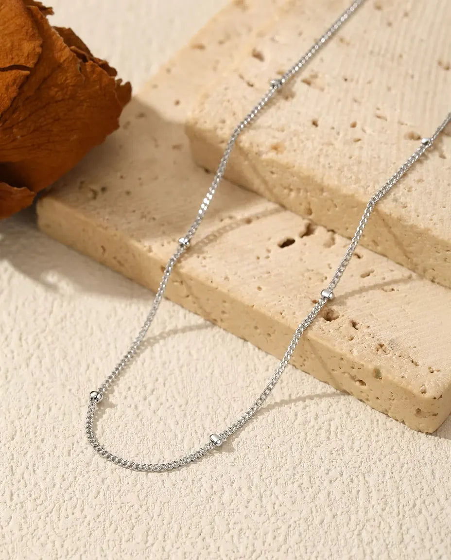Halsband med Satellitkedja i 925 Sterlingsilver - draperat på en ljus yta bredvid en travertinplatta