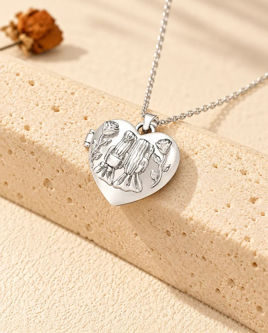 Personlig hjärtmedaljong med två systrar och rosor på locket, silverfärgad, lutad mot ett travertinblock