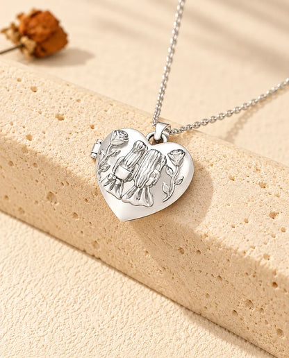 Personlig hjärtmedaljong med två systrar och rosor på locket, silverfärgad, lutad mot ett travertinblock