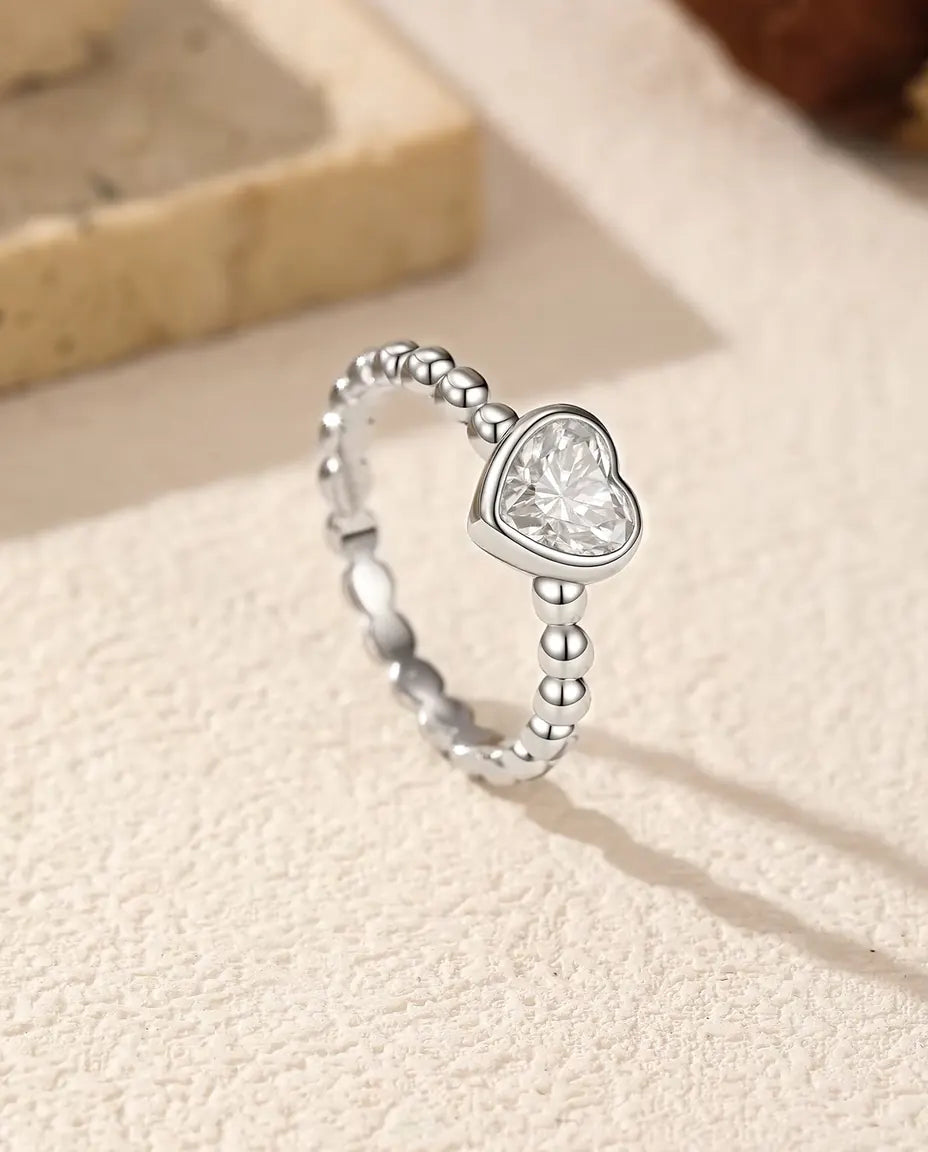 Moissanite Ring med Hjärta i 925 Sterlingsilver - stående på en ljus strukturerad yta