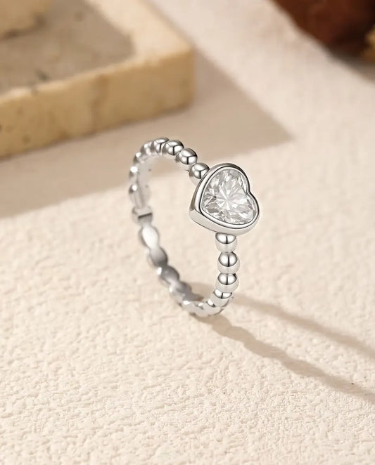 Moissanite Ring med Hjärta i 925 Sterlingsilver - stående på en ljus strukturerad yta