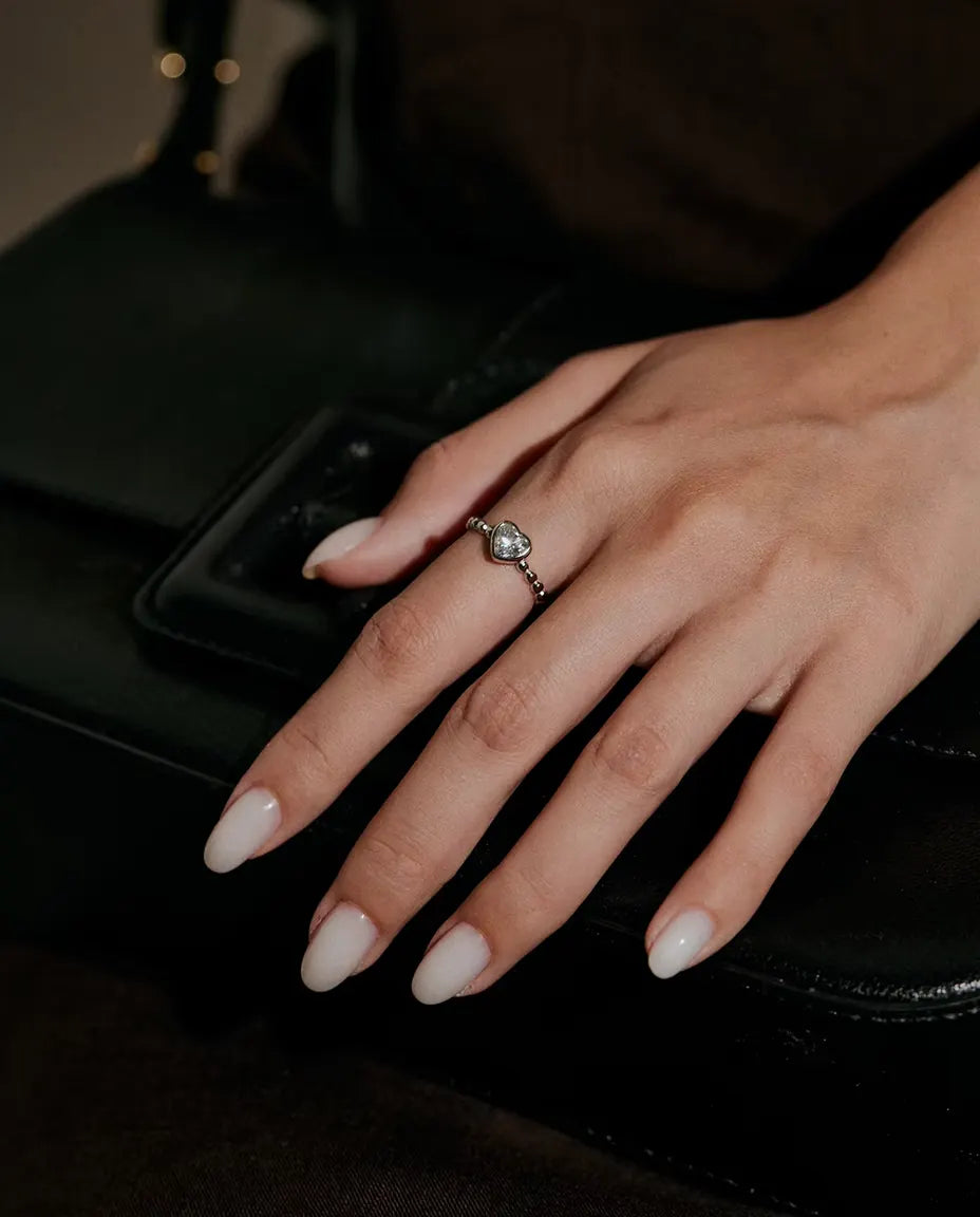 Moissanite Ring med Hjärta i 925 Sterlingsilver - buren på en hand som vilar på en svart väska