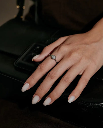 Moissanite Ring med Hjärta i 925 Sterlingsilver - buren på en hand som vilar på en svart väska