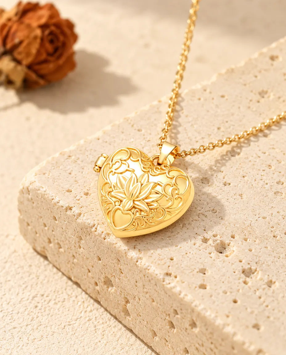 Guldfärgat halsband med hjärtmedaljong och lotusblomma i relief, draperat över ett travertinblock